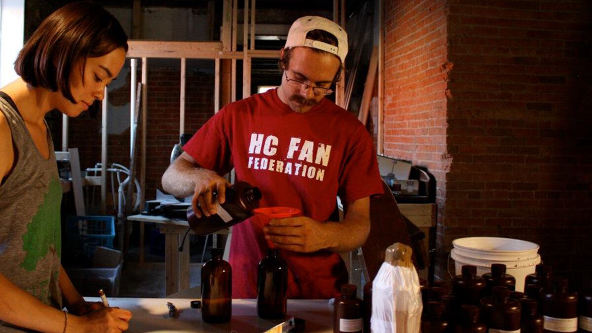 Abi and Andrew Vrbas filling amber bottles in an early Pacha Soap workspace