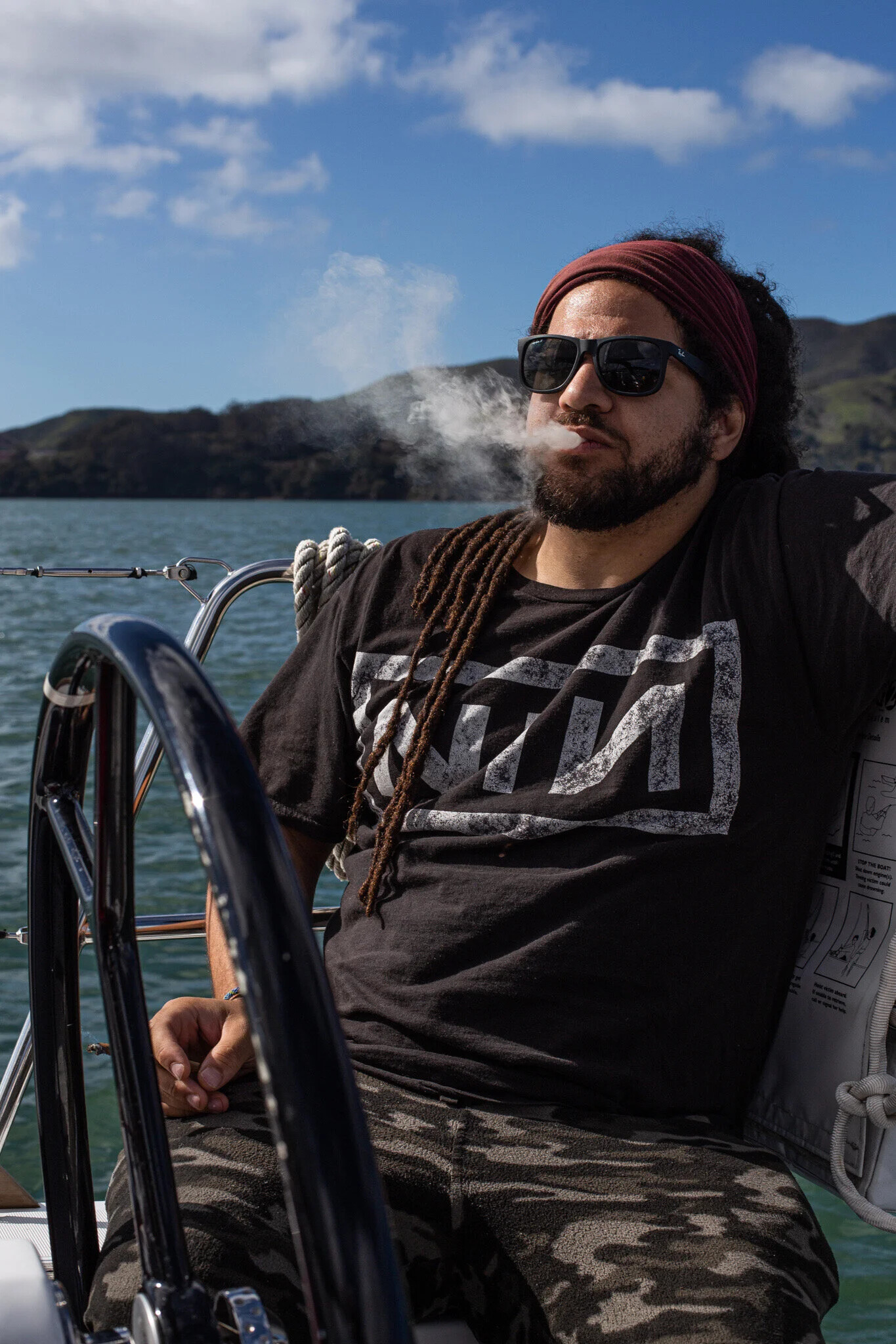 Andrew Watson sitting on a boat with water and hills behind him