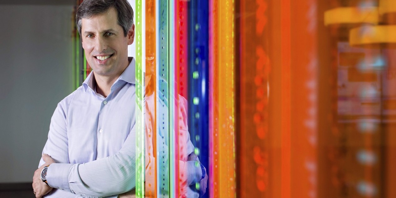 Andrew Zimakas standing beside translucent orange, blue and green panels during his Tangerine era