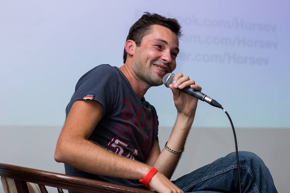 Andrey Horsev seated with a microphone during a public conversation