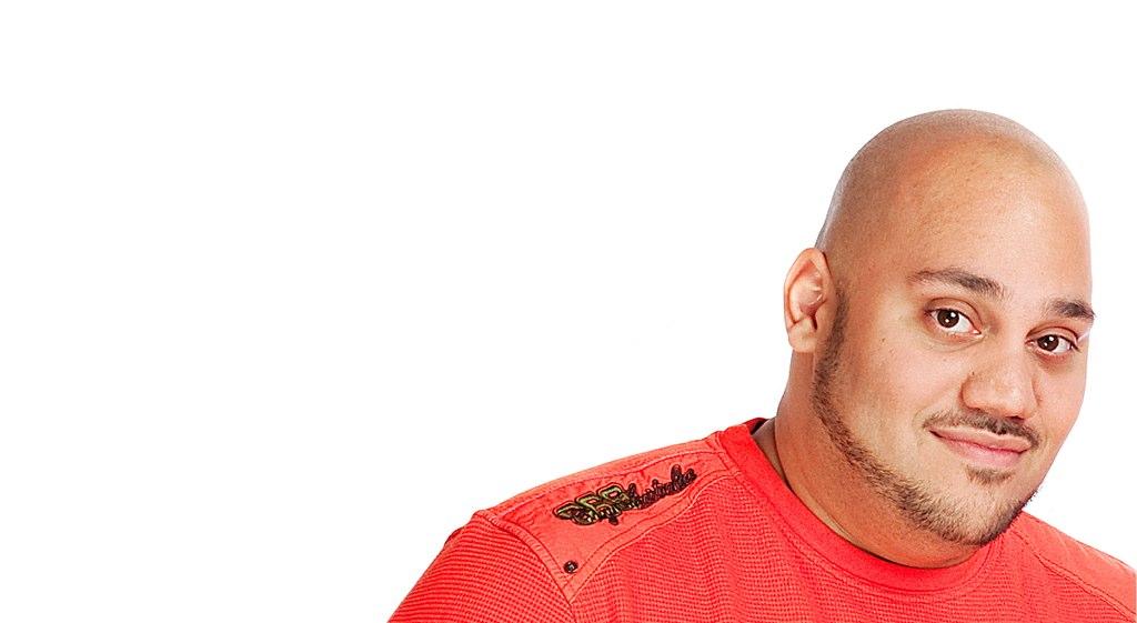 An earlier portrait of Andru Edwards in a red shirt against a light background