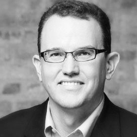Black-and-white portrait of Andy Clark in glasses and a jacket