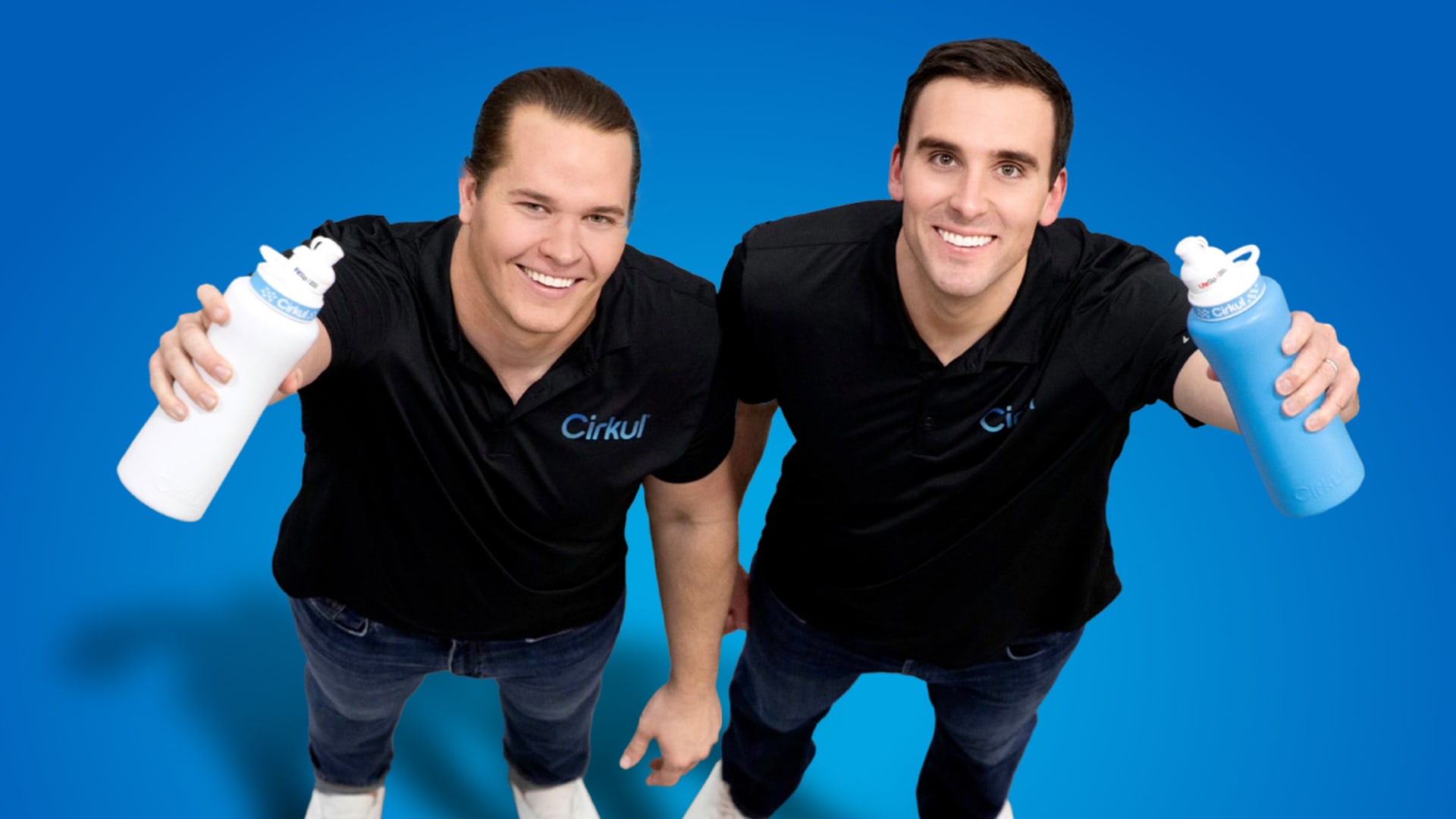 Cirkul co-founders Garrett Waggoner and Andy Gay holding reusable Cirkul bottles against a blue background