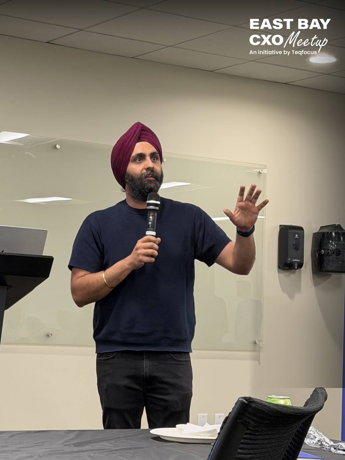 Andy Singh speaking into a handheld microphone at an East Bay CXO meetup