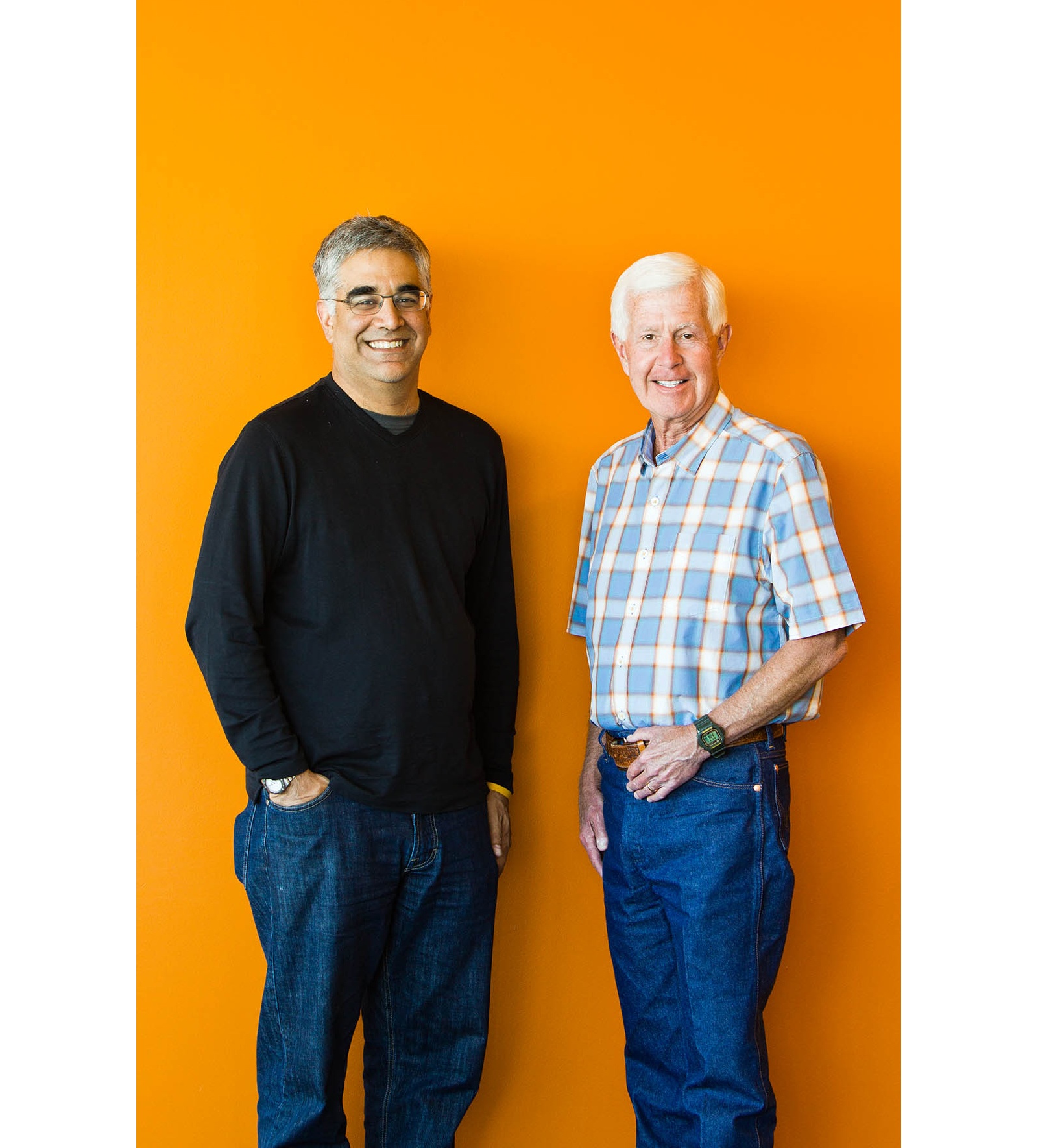 Aneel Bhusri, left, and Workday co-founder Dave Duffield standing together against an orange wall