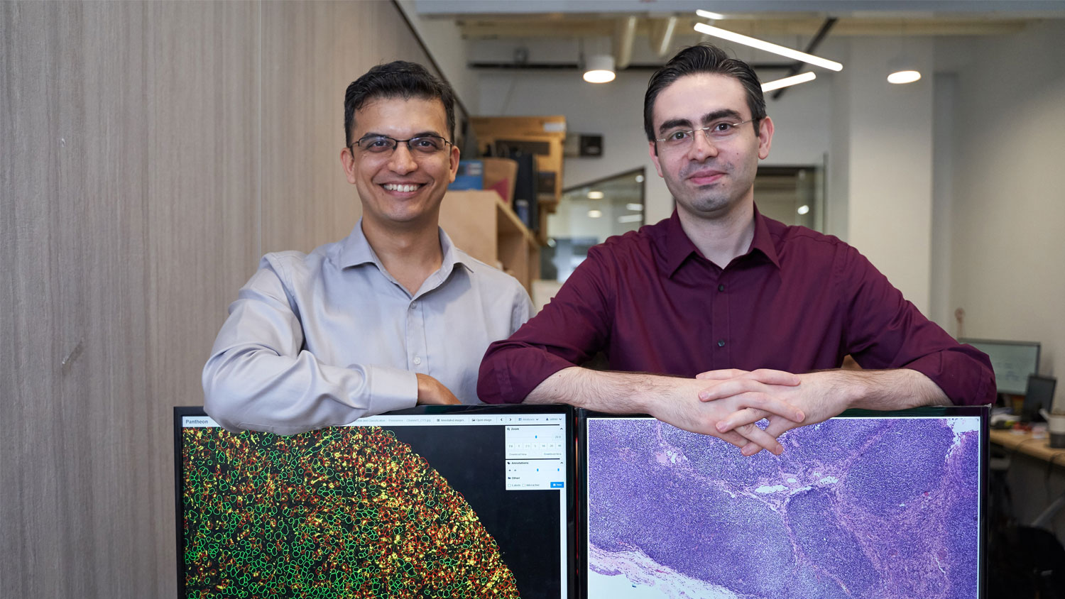 Aneesh Sathe on the left and Kaveh Taghipour on the right, standing together behind software displays