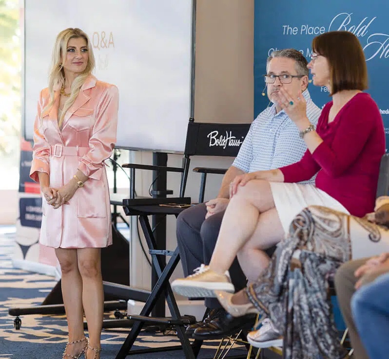 Angelique Rewers standing beside seated speakers during a BoldHaus discussion