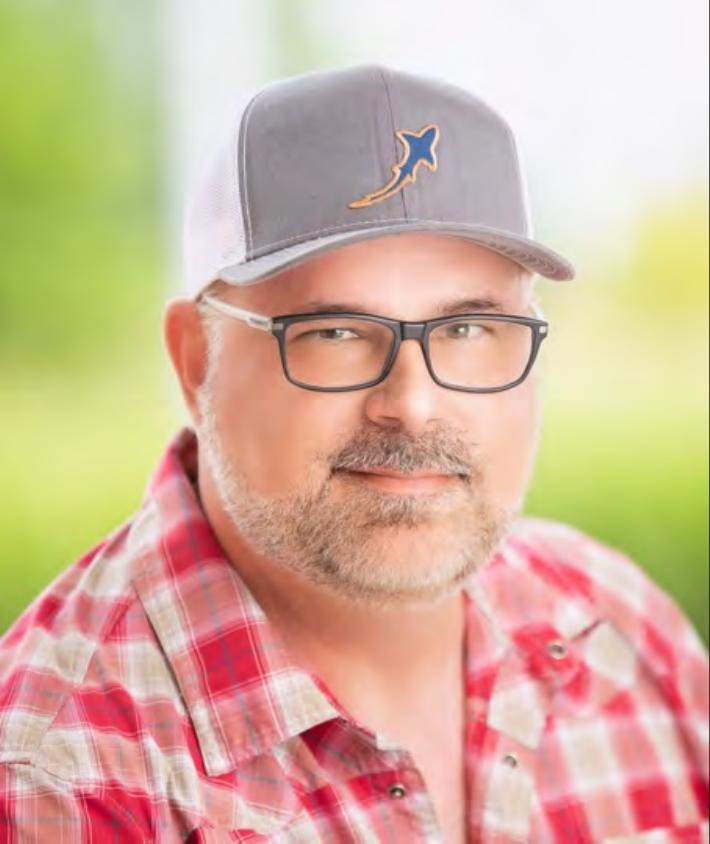 Angelo Antoline wearing glasses, a cap and a red plaid shirt