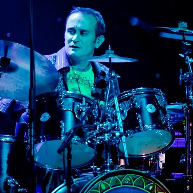 Angelo Frisina playing drums beneath blue stage lights