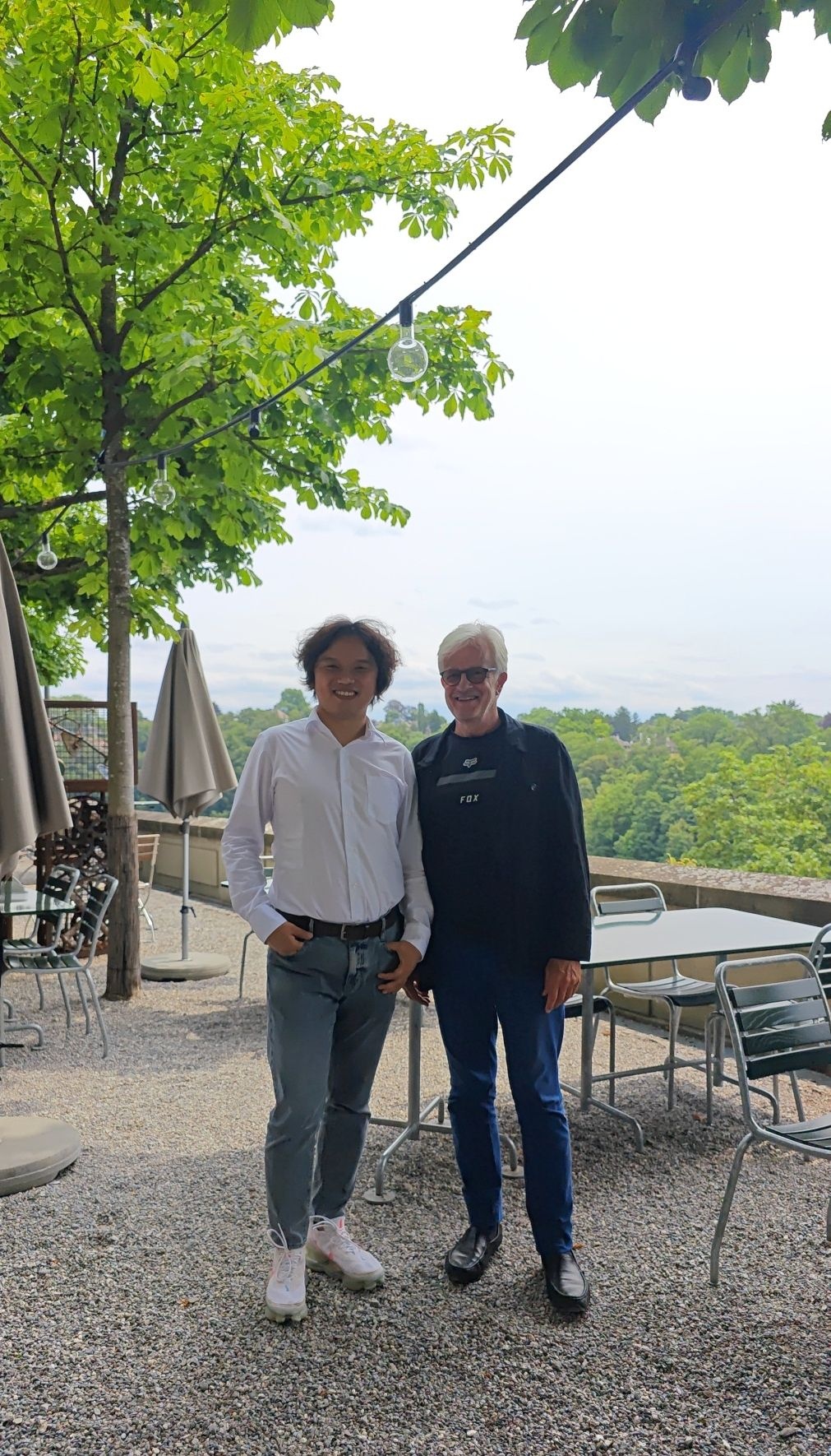 Angelo Yu standing with filmmaker Jürg Neuenschwander outdoors in Switzerland