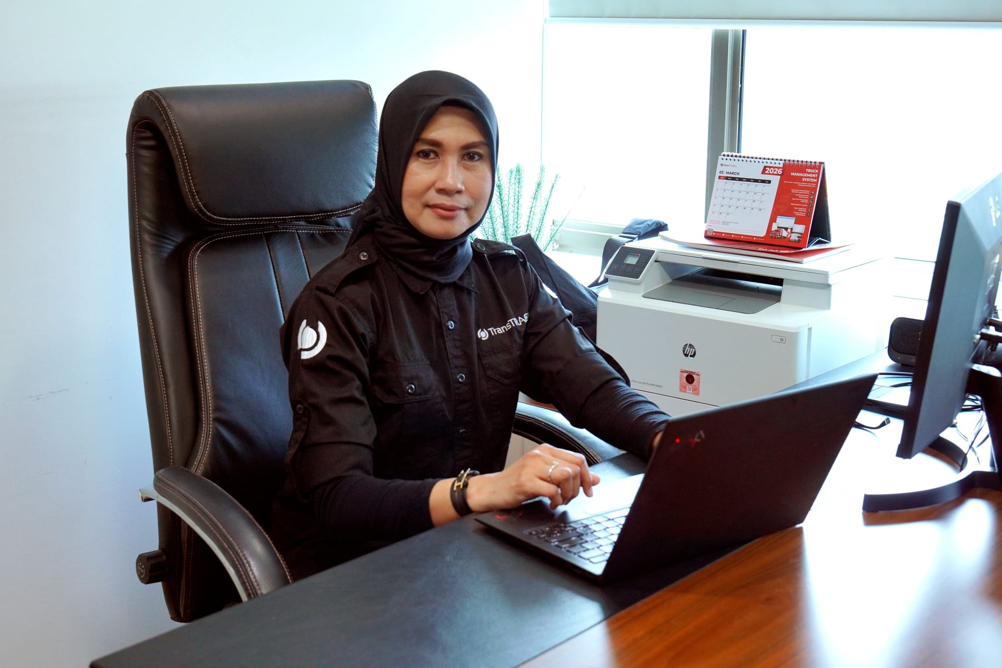 Anggia Meisesari seated at her desk with a laptop in her Jakarta office