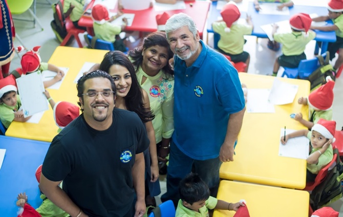 Anik and Andrea Singal with Naomi and Ian Hendricks in a classroom, surrounded by children at colourful tables