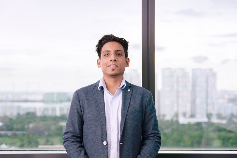 Aniket Singh Rajput standing beside a large office window