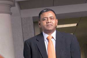 Archival photograph of Anil Kumar in a dark suit and orange tie