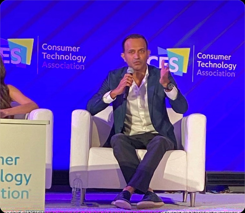 Anil Mathews seated onstage, speaking into a microphone at a Consumer Technology Association panel