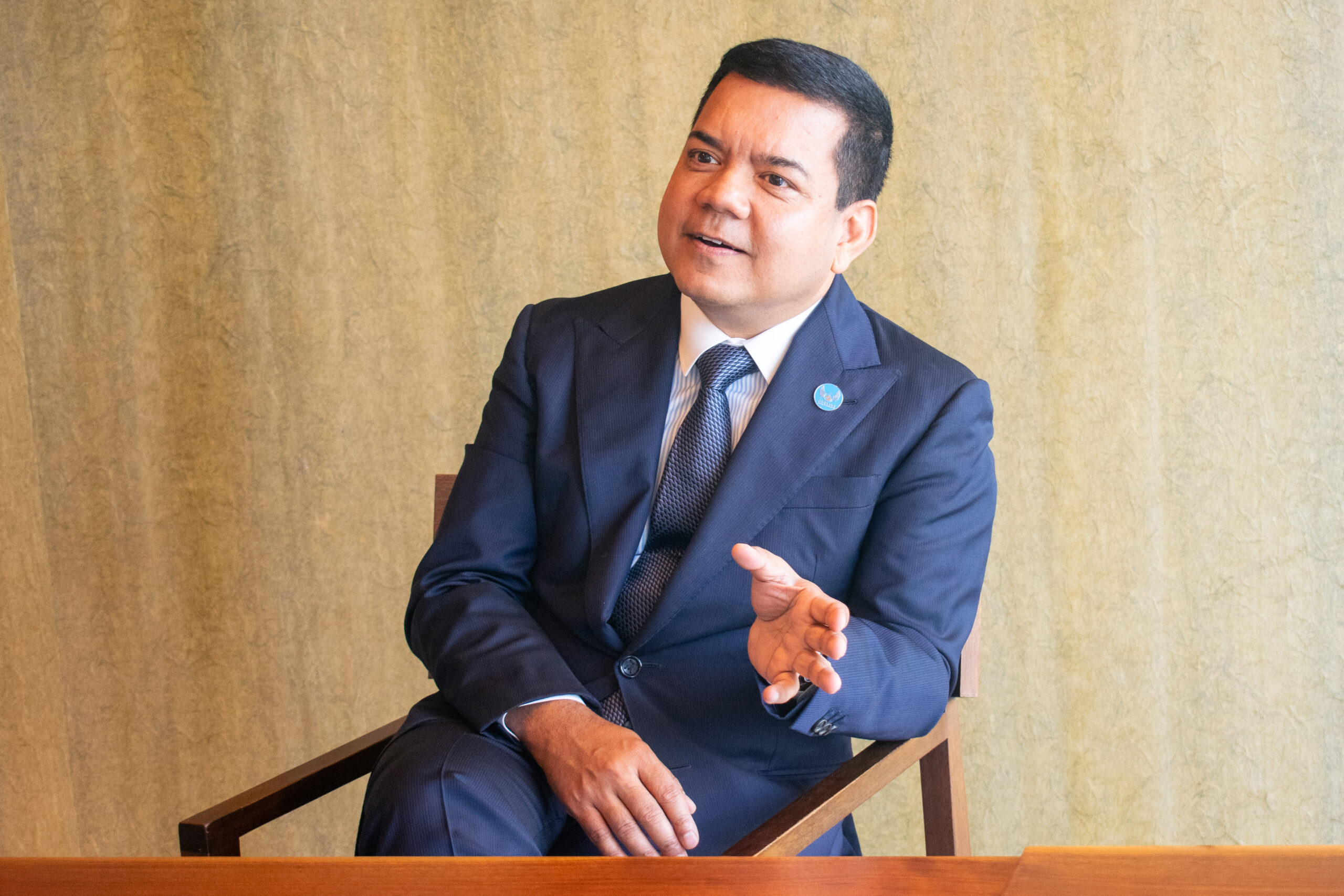 Anis Uzzaman speaking and gesturing during a seated interview in Tokyo
