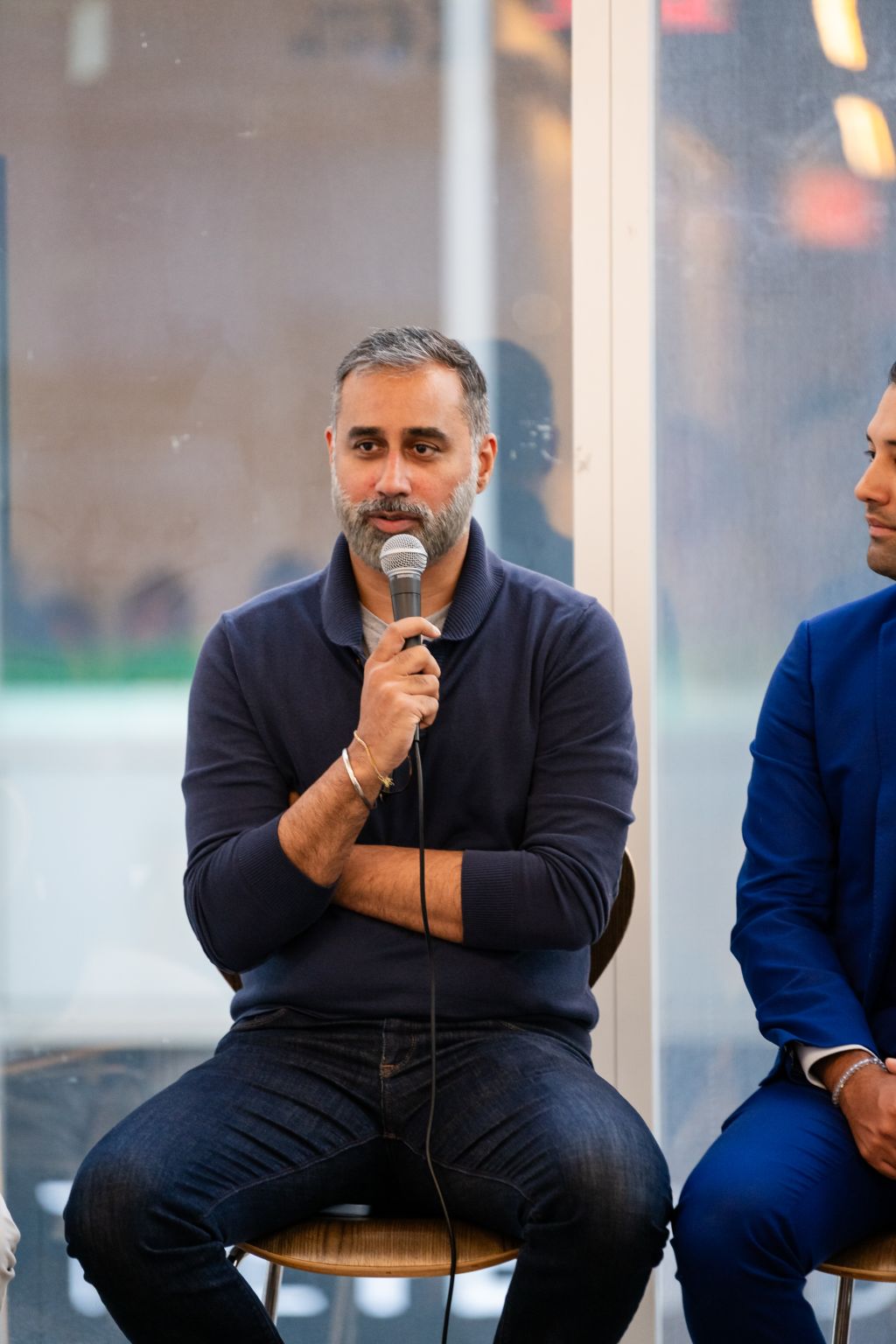 Anish Malhotra speaking into a microphone during a real-estate investment panel in New York