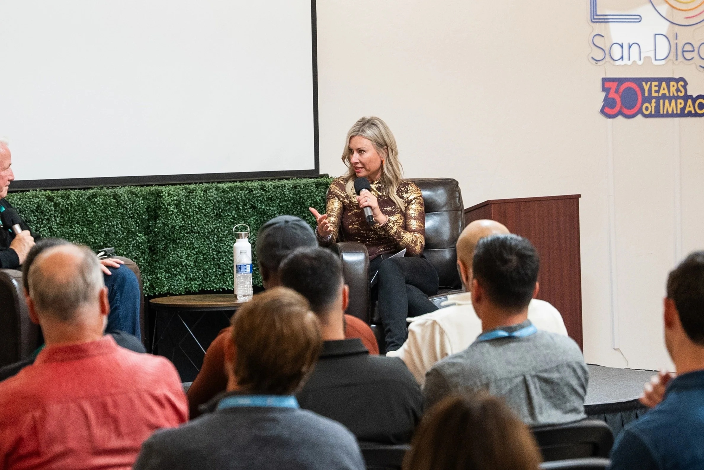 Anna Crowe speaking into a microphone at an Entrepreneurs’ Organization San Diego event