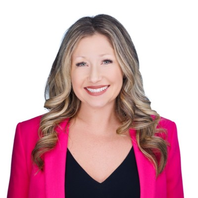 Anna Fisher smiling in a bright pink blazer against a light background