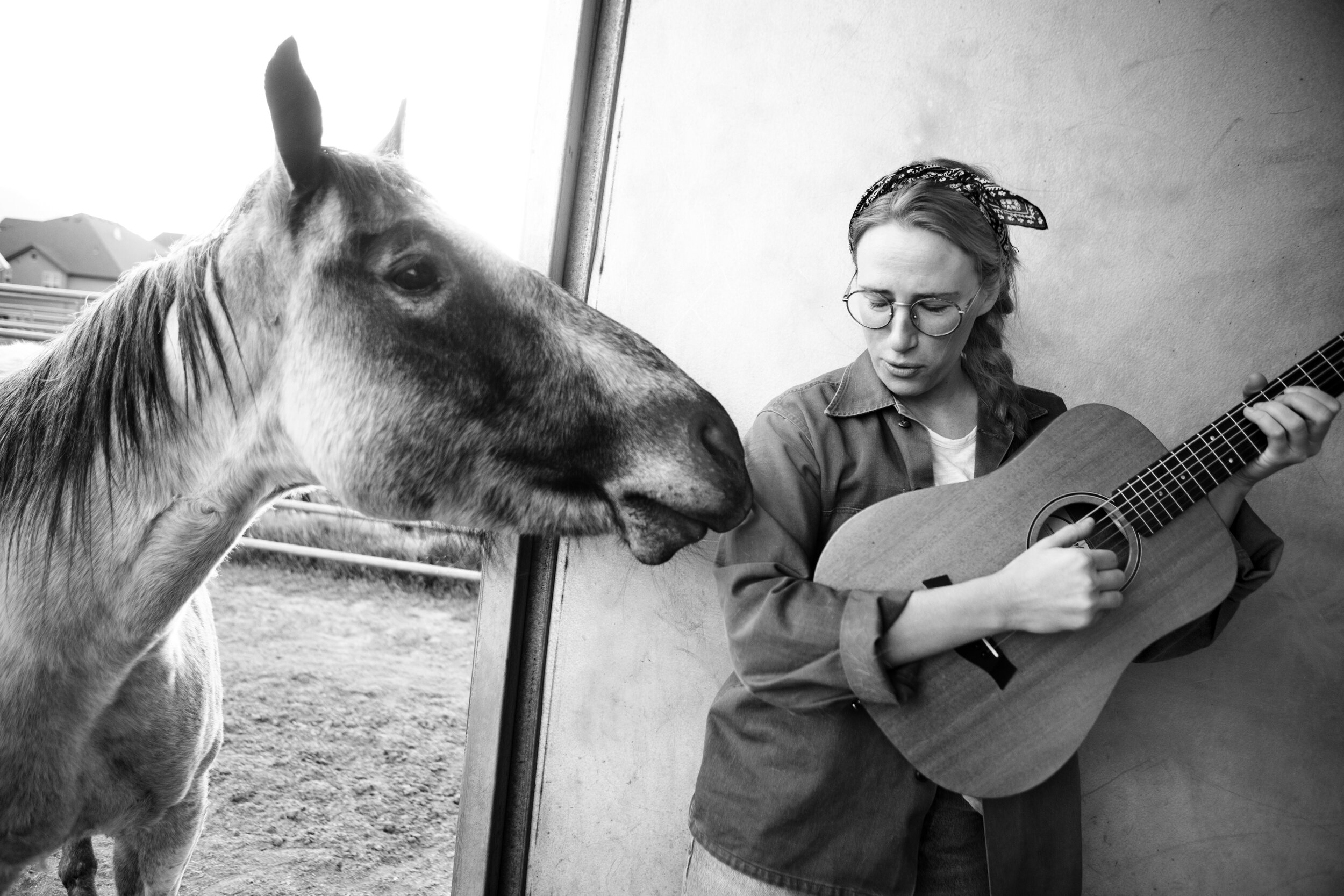 Anne Armistead holding a guitar beside a horse at a ranch
