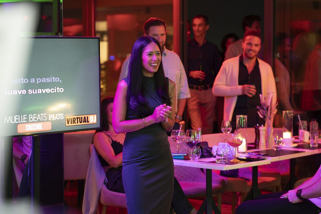 Anne Ghaltchi smiling during an evening event, with guests gathered behind her