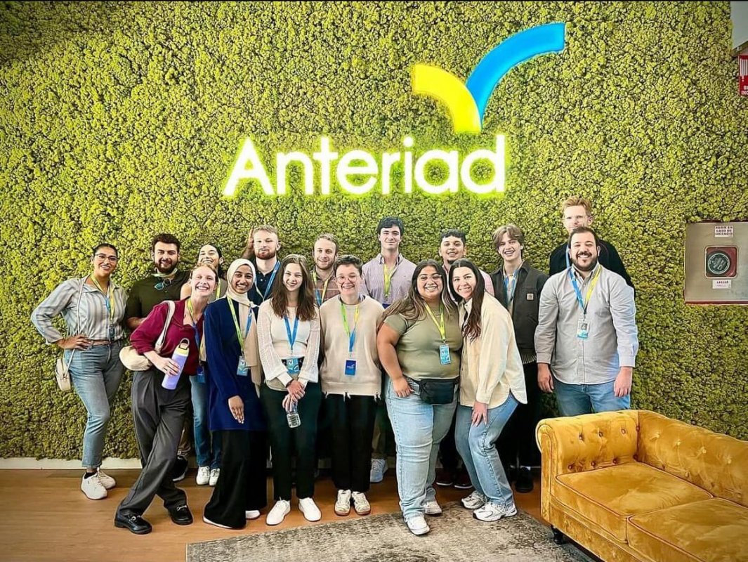 Students and professionals visiting Anteriad's Madrid office in front of a moss wall and company sign
