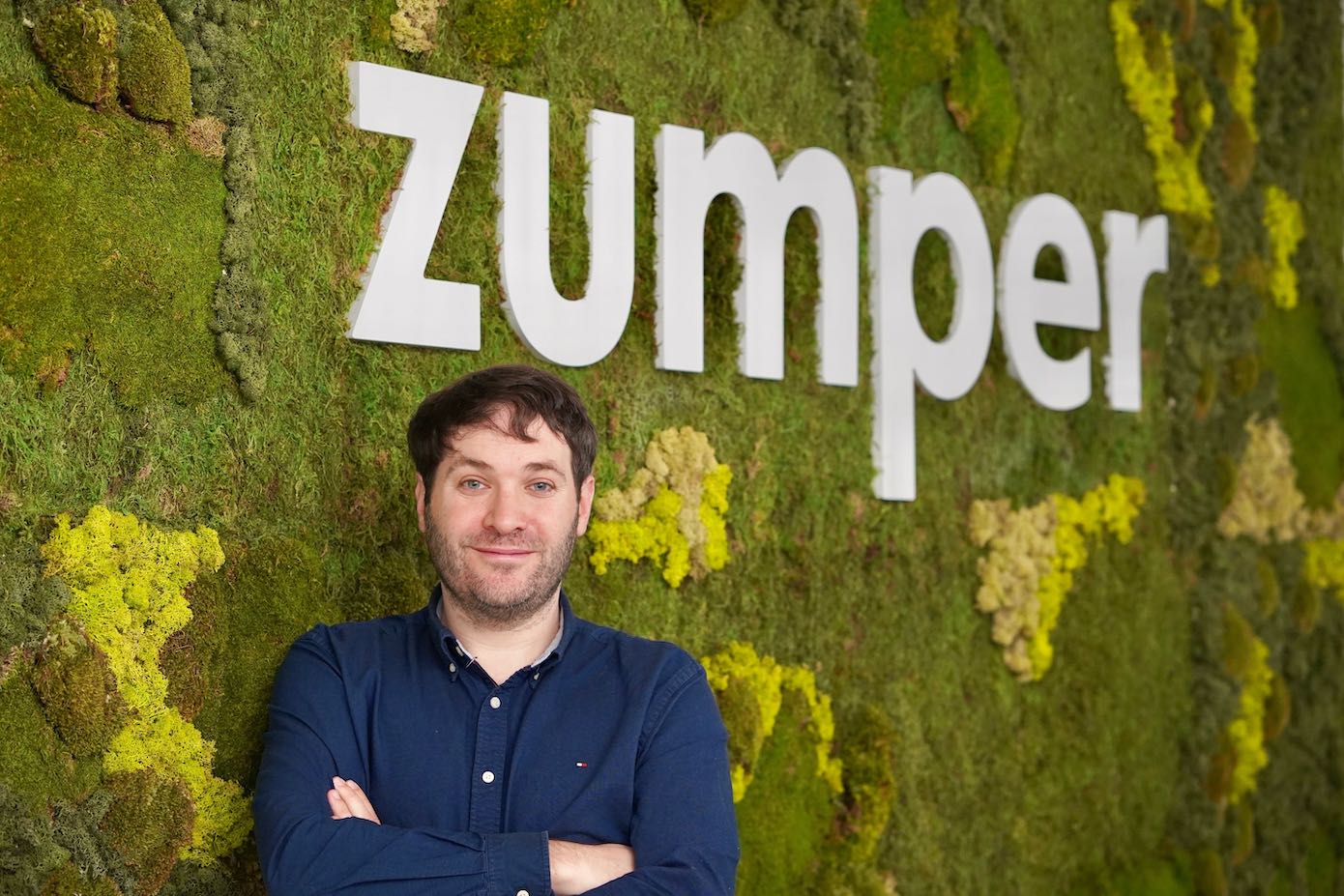 Anthemos Georgiades standing in front of Zumper’s green wall and company sign
