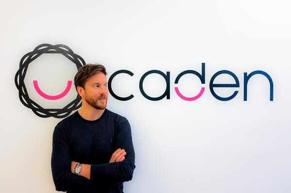 John Roa standing beside the Caden wordmark