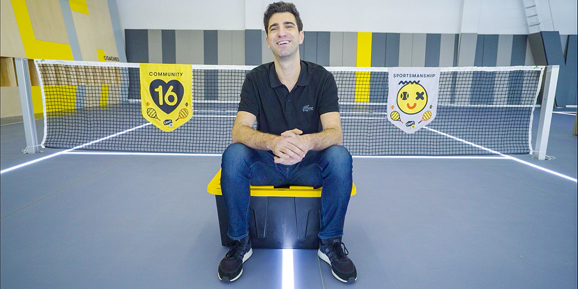 Anthony Evrard seated on an indoor court with illuminated floor lines and community and sportsmanship banners