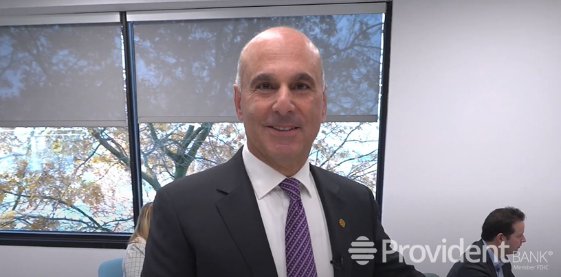 Tony Labozzetta in a Provident Bank office, wearing a suit and purple tie