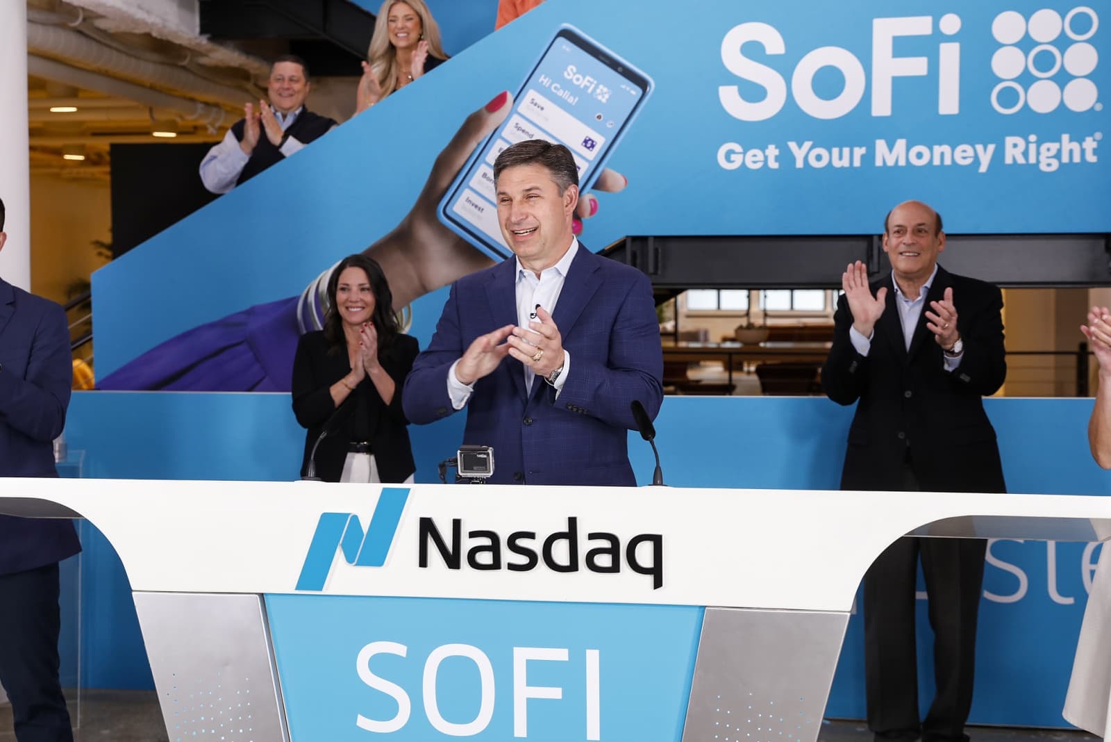 Anthony Noto applauding at a Nasdaq podium with SoFi colleagues and company branding behind him