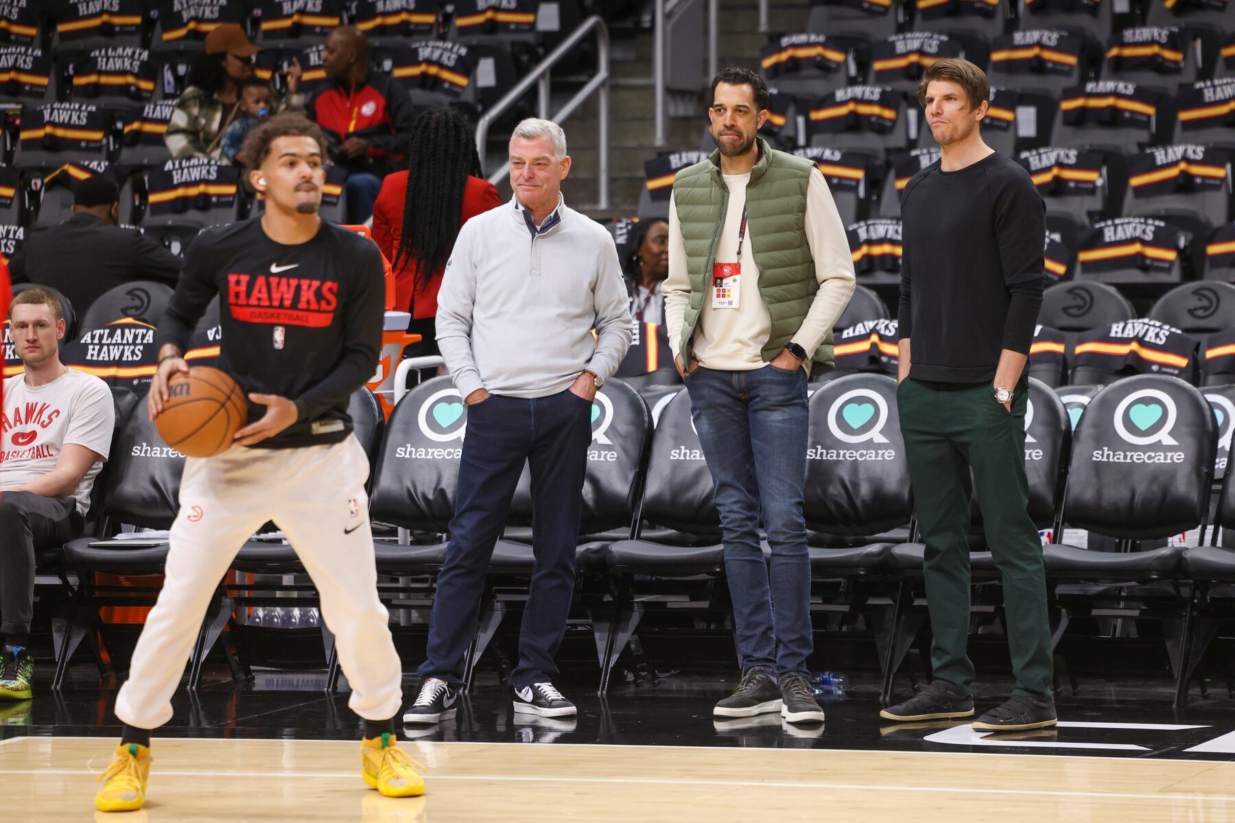 Tony Ressler watches courtside with Landry Fields and Kyle Korver as Trae Young prepares a shot in February 2023.