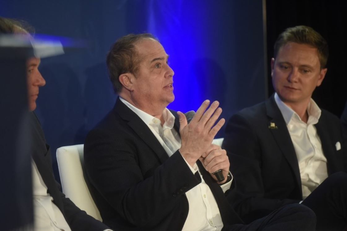 Anthony Singer, seated in the center, speaks into a microphone on an SBC conference panel.