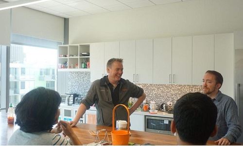 Anthony Smith standing at a kitchen counter in conversation with members of the Insightly team