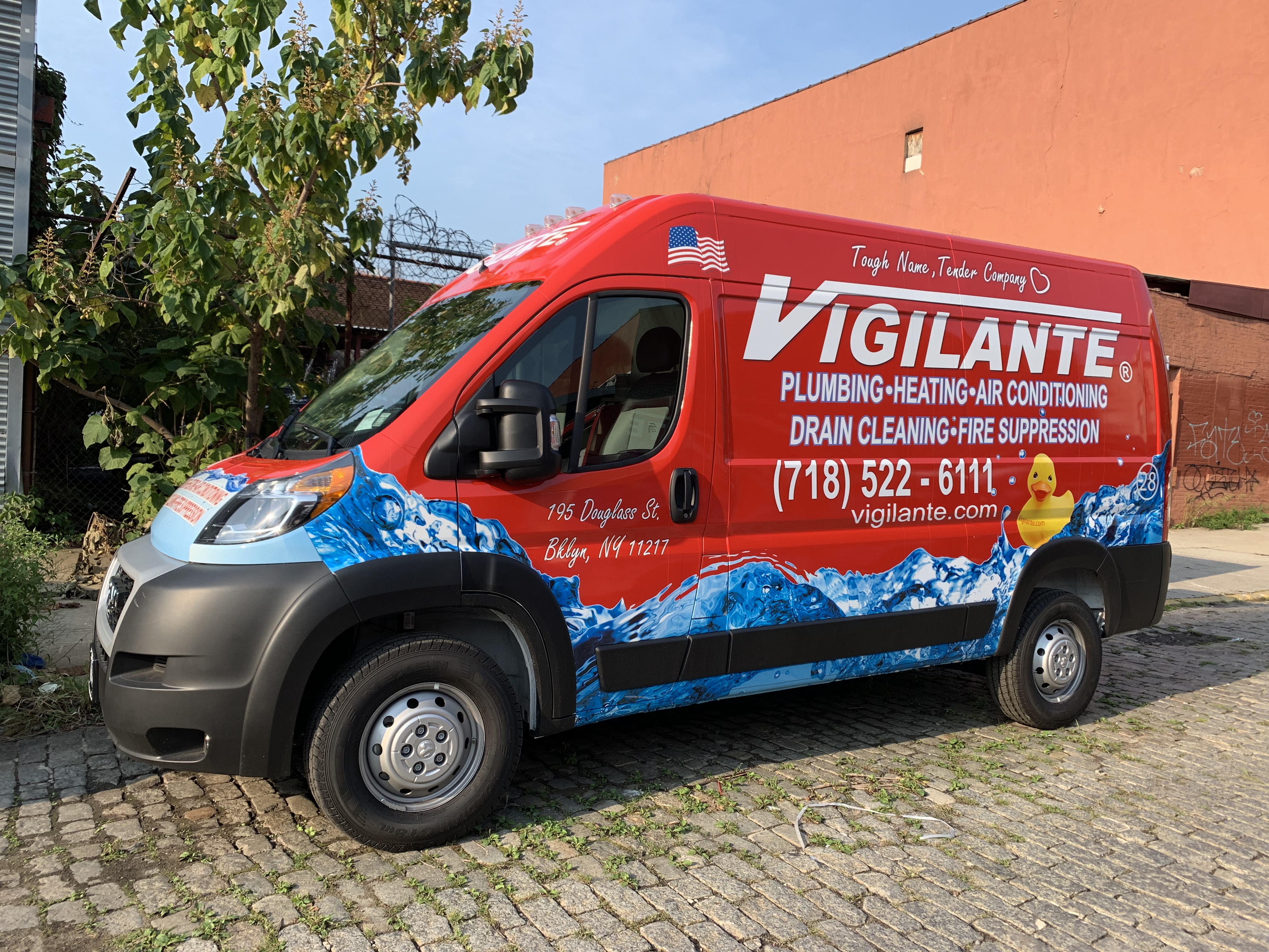 A red Vigilante Plumbing service truck parked on a Brooklyn street