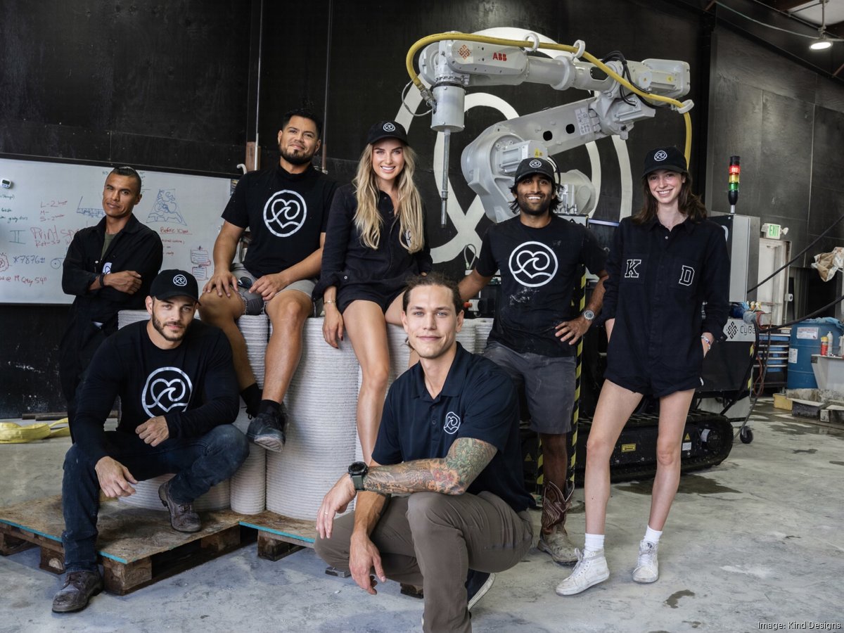 Kind Designs founder Anya Freeman and colleagues gathered around an industrial robotic printer in their Miami warehouse