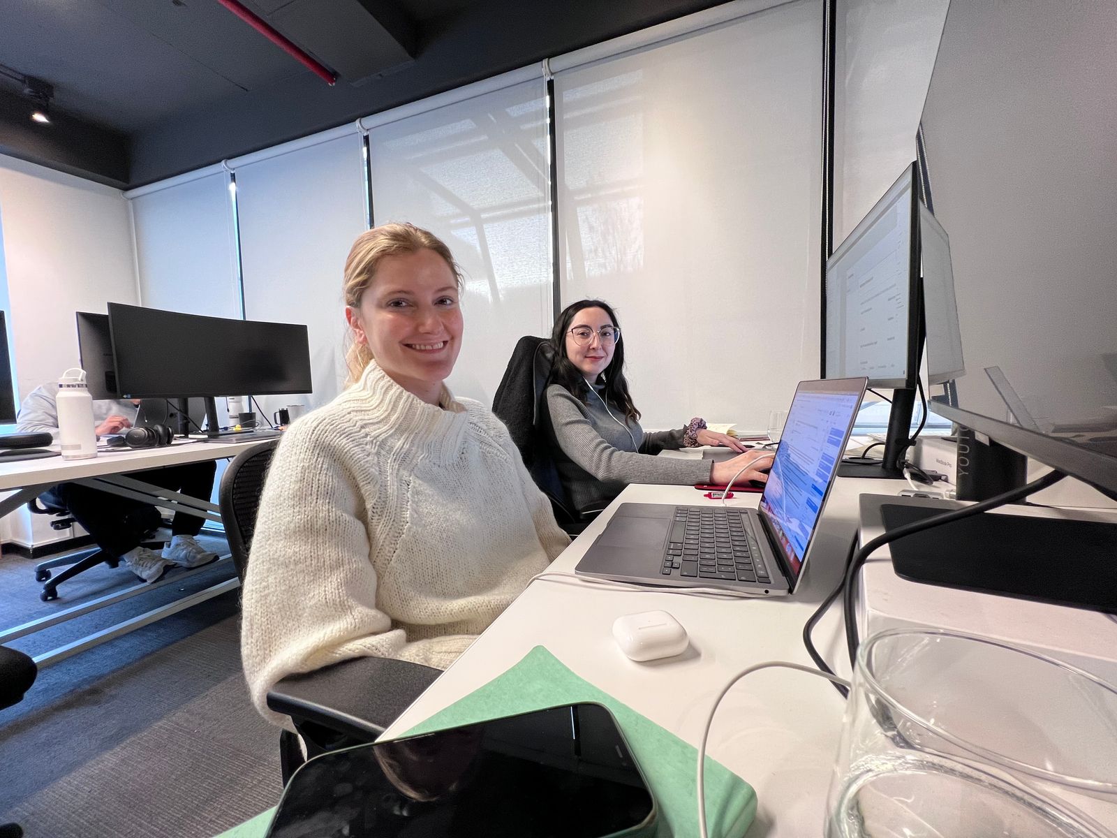Antonia San Martín Sola seated at her laptop with members of the Plutto team in their office