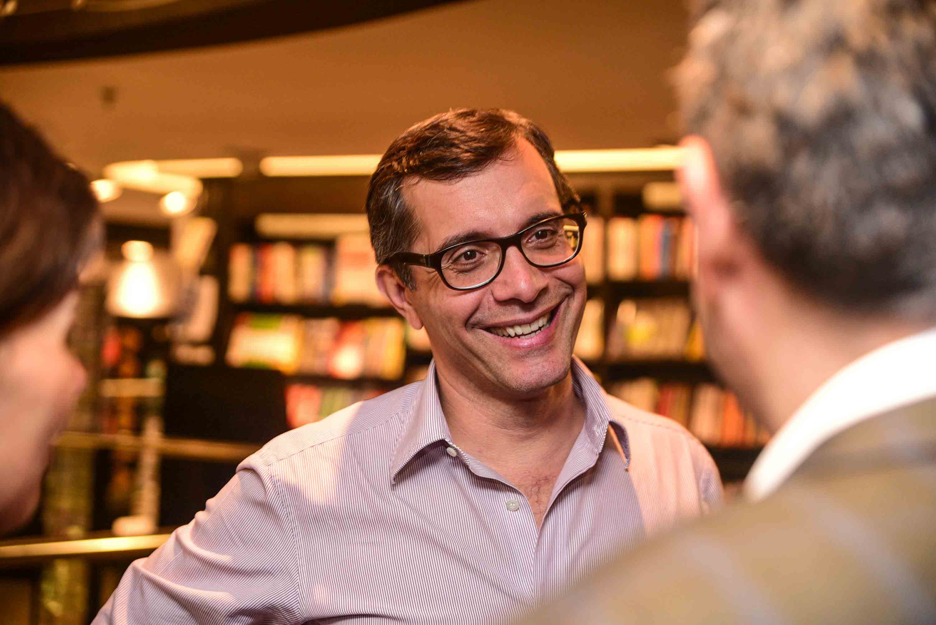 Antonio Bonchristiano smiling in conversation with two people, with bookshelves behind him