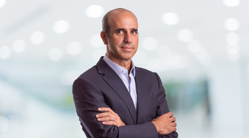 Antonio Pereira standing with his arms folded in a bright office