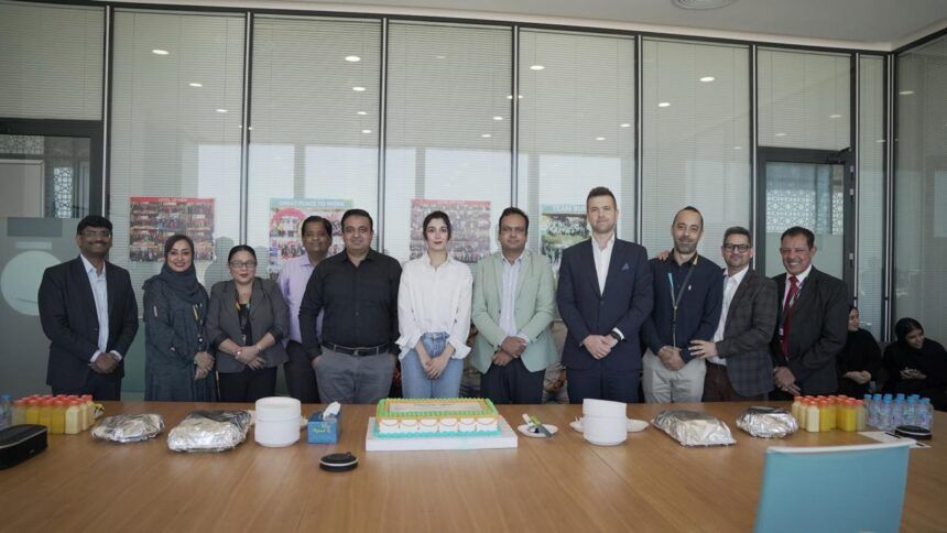 Team members gathered around a celebration cake at the Muscat Duty Free platform launch