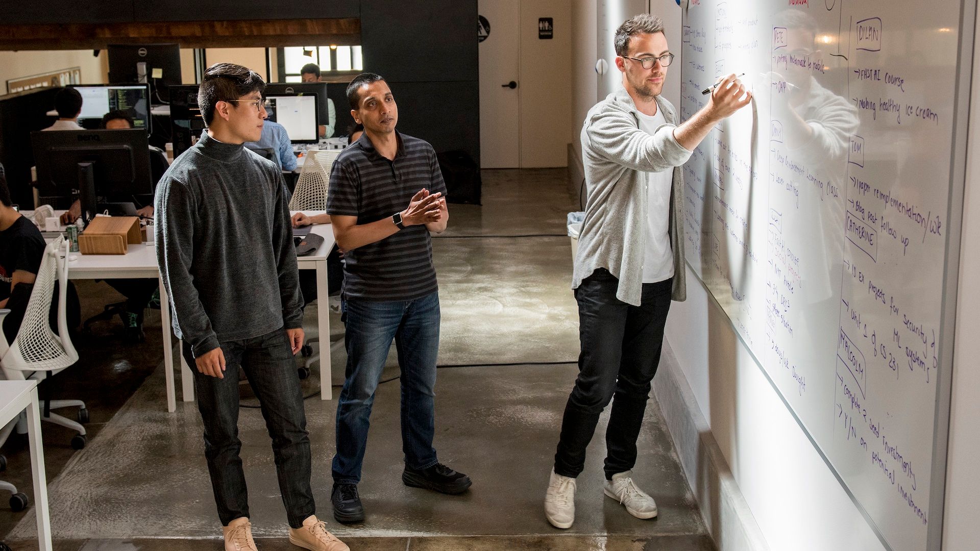 Anurag Goel, center, collaborating with two South Park Commons members beside a whiteboard