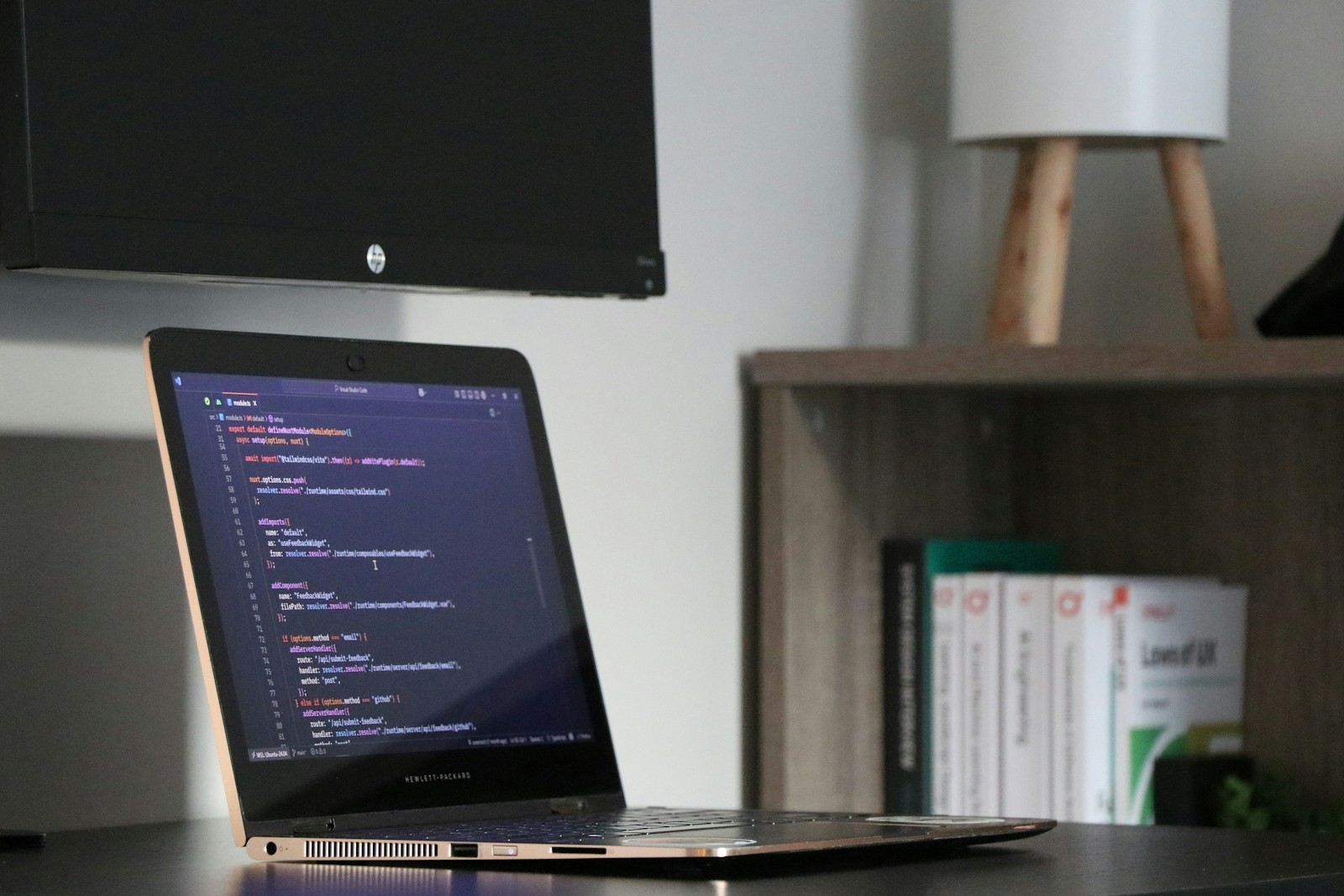 Laptop displaying source code on a desk in a softly lit workspace