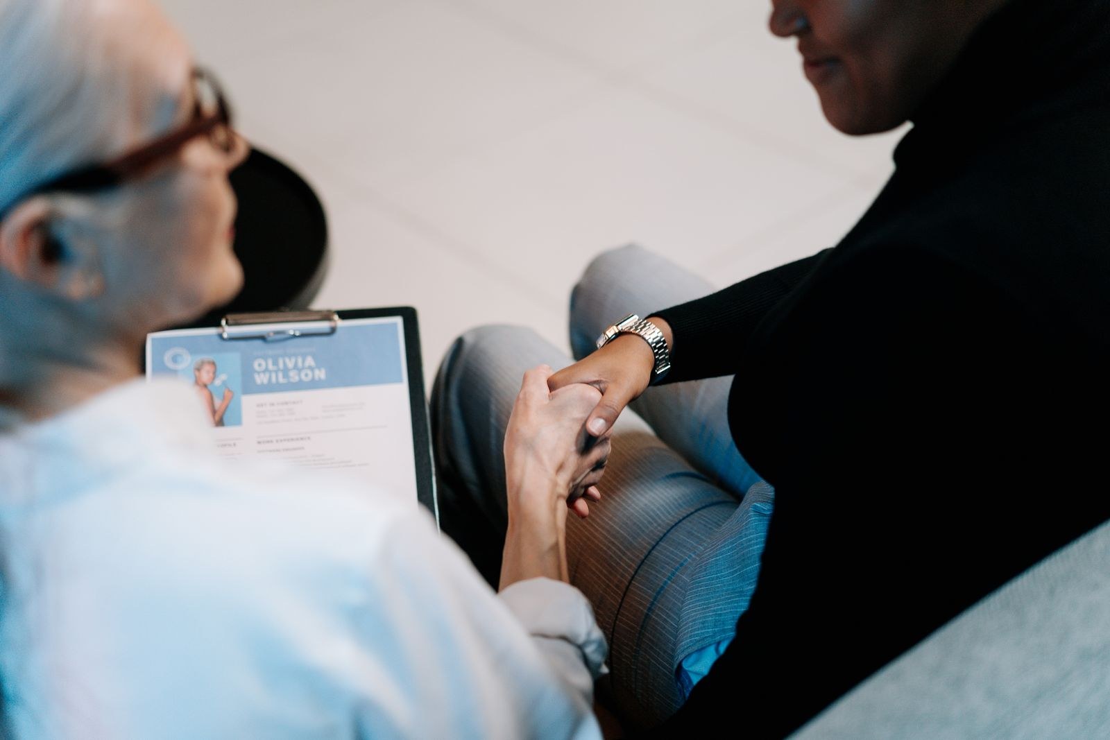 A candidate and interviewer shake hands beside a résumé