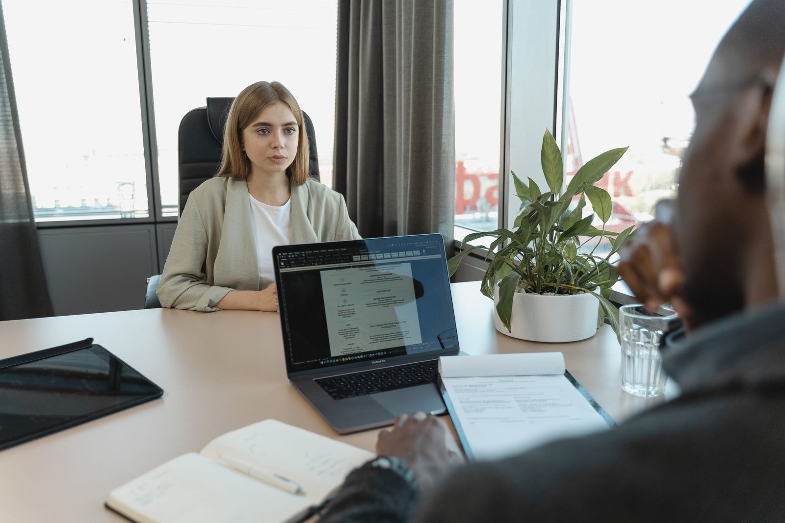 A job candidate speaks with an interviewer, with a résumé open on a laptop between them