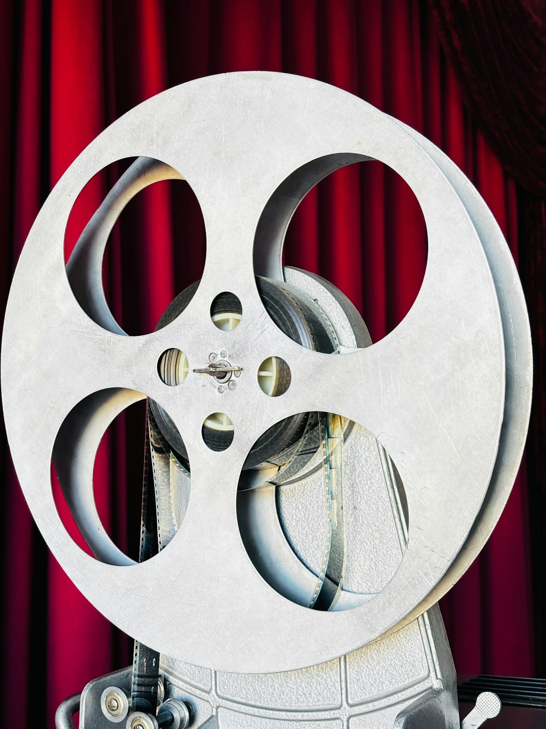 A metal film reel against a red velvet curtain