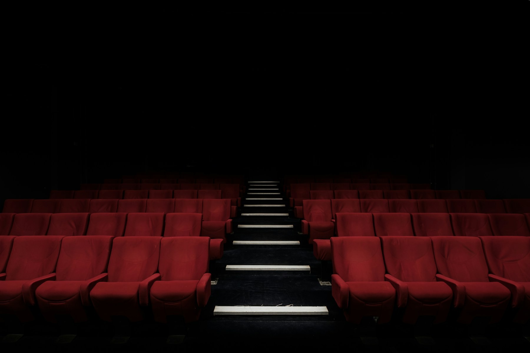 Rows of red seats in a dark, empty cinema