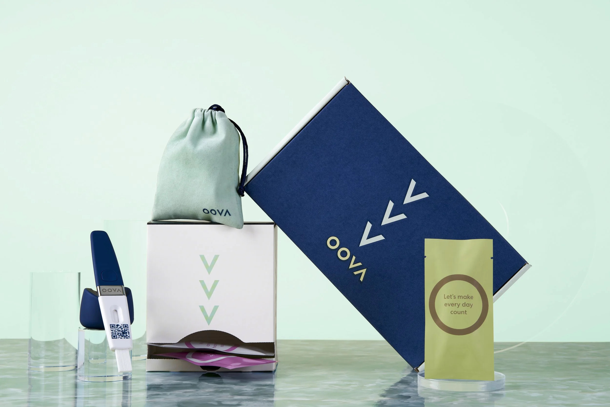 An Oova testing kit arranged with its navy packaging and phone-readable test holder