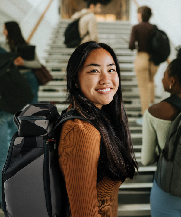 Young Asian woman carrying a backpack on a staircase in a public-health career campaign