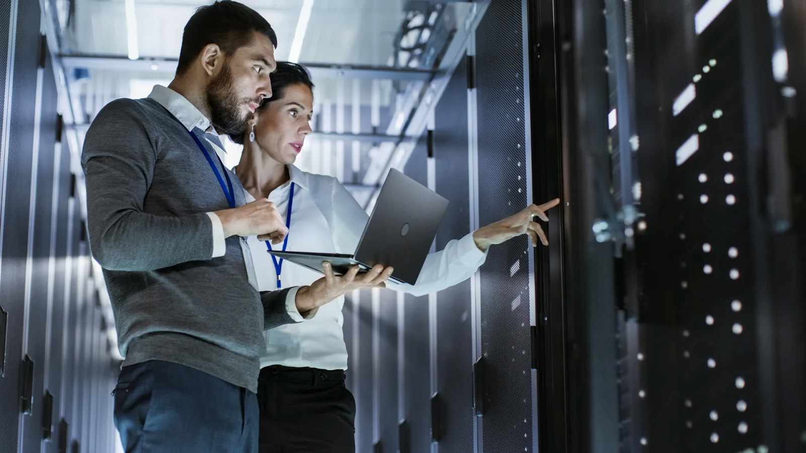 Two people inspecting a server rack with a laptop