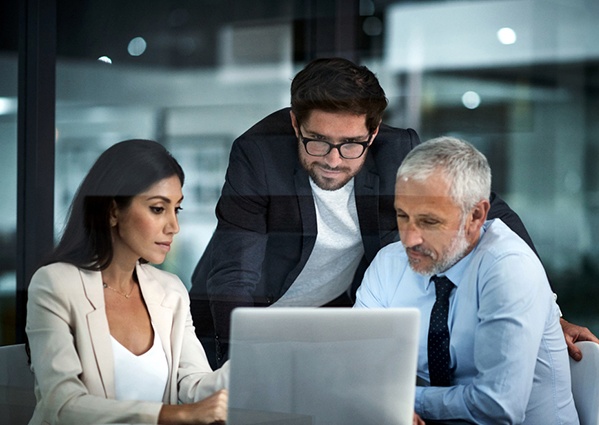 Three people reviewing a laptop, an illustrative photograph from Apixio’s Capital Blue Cross brochure